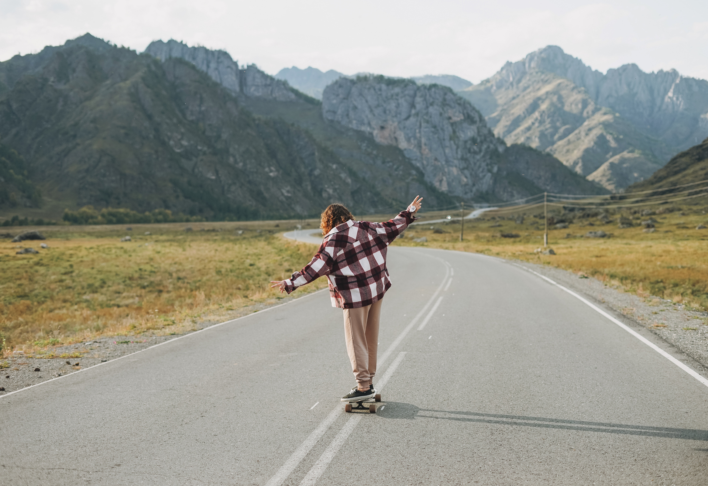 Person on Skateboard on Road against Beautiful Mountain Landscape